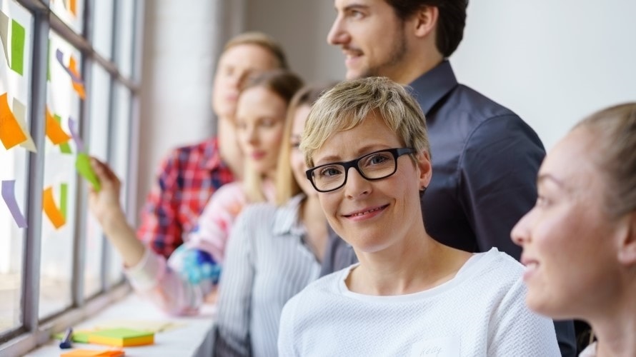 Bilde av glade kollegaer som har en workshop med fargede lapper.