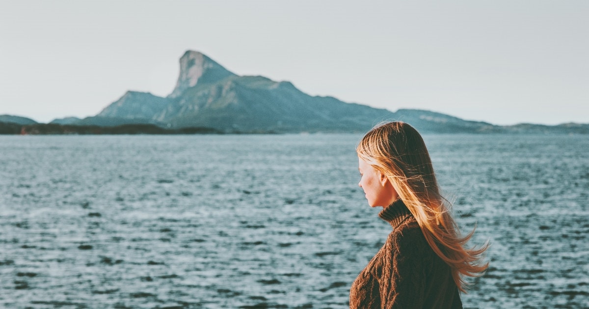 Kvinne ser utover havet. Foto.